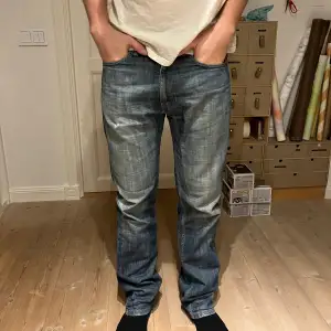 Säljer ett par klassiska blå Levi's jeans i bra skick. De har en straight passform i storlek 32/34. Lite slitna runt fickan och knät. 