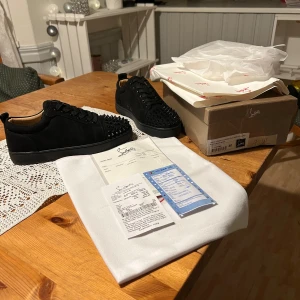 Christian Louboutin Skor - Säljer ett par svarta sneakers från Louboutin i nytt skick, Max använda 3 gånger. De har en cool design med nitar på ovansidan och den ikoniska röda sulan. Skorna är gjorda i skinn och kommer med originalförpackning och kvitto. Pappa köpta dom som present när han var i Frankrike på jobb resa.  Skriv om du några frågor MVH. 