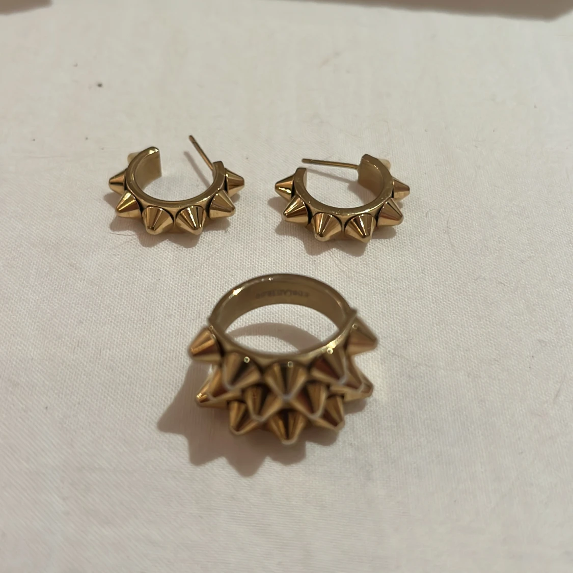 Guldiga örhängen och ring med nitar