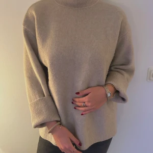 Beige stickad polotröja - Mysig beige stickad polotröja. Den har en avslappnad passform med långa ärmar och ribbade muddar. Tröjan är både stilren och bekväm, idealisk för höst och vinter. Passar bra till både jeans och kjol för en casual look.