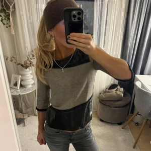 Grå och svart topp med trekvartsärm - Säljer en snygg grå topp med svarta skinn detaljer och trekvartsärmar. Perfekt för både vardag och fest! ❣️❣️
