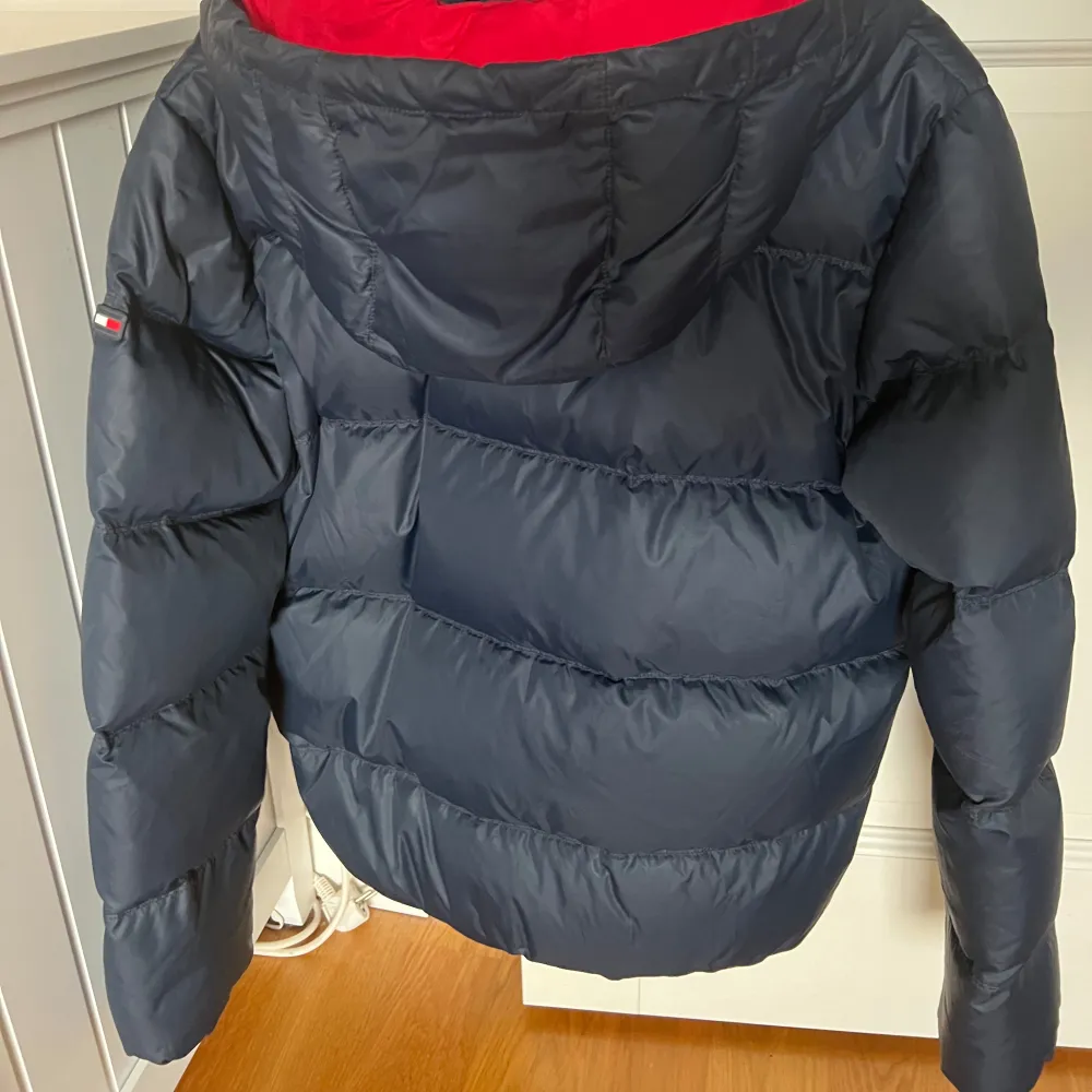 Säljer en snygg blå dunjacka från Tommy Hilfiger i storlek 176. Jackan har en cool röd insida och en praktisk huva. Perfekt för kalla vinterdagar med sin varma och puffiga design. Den har en dragkedja framtill och är i mycket bra skick. Passar både till vardags och lite finare tillfällen.. Jackor.