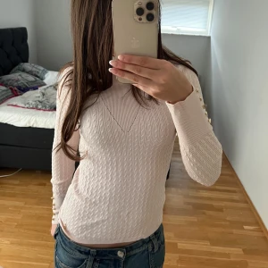 Vit ribbad tröja med knappar - Säljer en snygg vit ribbad tröja med långa ärmar och dekorativa knappar längs ärmarna. Perfekt för både vardag och fest! Tröjan har en tight passform och är superbekväm. Passar perfekt till jeans eller kjol. 🖤