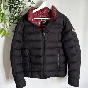 Svart pufferjacka från Colmar - Säljer en snygg svart pufferjacka från Colmar i mycket bra skick. Jackan har en cool röd insida och är perfekt för höst och vinter. Den har dragkedja och praktiska fickor. Passar perfekt för både vardag och festliga tillfällen. Håll dig varm och stilren! 🖤