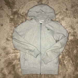 Lacoste Zip Hoodie - Storlek Xs, köpt ifrån Lacoste på Barkarby outlet. Tröjan är i nyskick och har använts väl. Ställ gärna frågor och skicka prisförslag.😃