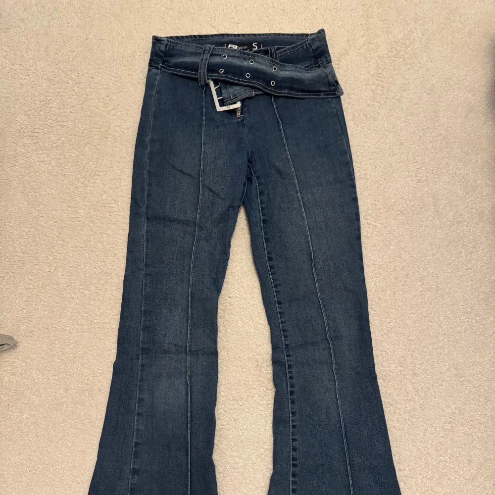 Säljer ett par snygga mörkblå low/mid waist bootcut jeans i mycket bra skick. De är högmidjade och har en klassisk femficksdesign med en dragkedja och knappar framtill. Perfekta för både vardag och fest! Knappt använda! 🤍. Jeans & Byxor.