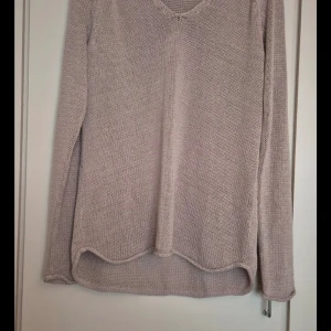 Beige stickad tröja från H&M - Mysig beige stickad tröja från H&M i storlek M. Perfekt för kyliga dagar med sin mjuka och bekväma passform. Tröjan har en v-ringad hals och långa ärmar, vilket gör den idealisk för både vardag och avslappnade tillfällen.