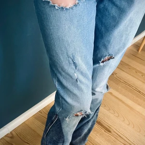 Blå slitna jeans från Levi's - Säljer ett par snygga blå jeans från Levi's i en avslappnad stil. De har en cool slitning på knäna och är i ett klassiskt denim-material. Perfekta för en casual look och passar till det mesta. De är i bra skick och redo för nya äventyr!