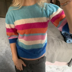 Färgglad randig tröja från Suncoo - Superfin och färgglad randig tröja från Suncoo i storlek S. Den har en härlig mix av blå, rosa, orange och vit med trekvartsärmar och mohair som ger den den fina texturen. Perfekt för att liva upp garderoben! 🥰