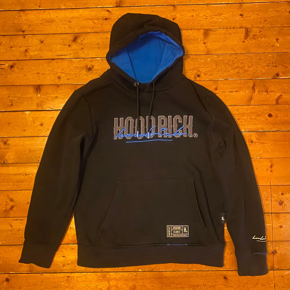 Säljer en snygg svart hoodie från Hoodrich med blå detaljer. Storlek M. Den har en stor ficka fram och en justerbar huva med blått foder. Perfekt för höst och vinter, och den är i mycket bra skick. Passar perfekt för en casual look eller träning.. Tröjor & Koftor.