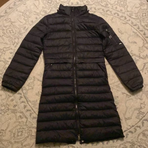 Svart dunjacka från CRW - Säljer en svart lång dunjacka från CRW i mycket bra skick. Jackan har en dragkedja framtill och långa ärmar. Den har även knappar där bak så den går att rida i. Pris kan eventuellt diskuteras😊😊Nypris:799kr