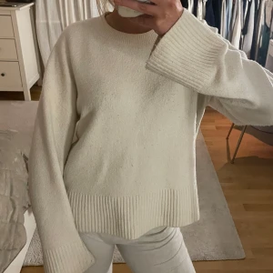 Vit stickad tröja - Mysig vit stickad tröja med långa ärmar och ribbade detaljer vid ärmslut och nederkant. Bra skick, lite nopprig! 