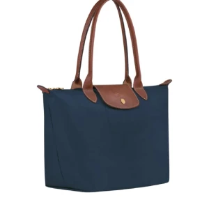 Mörkblå väska - Snygg och praktisk blå axelväska med bruna skinnhandtag och detaljer. Väskan har en dragkedja och en knapp för extra säkerhet. Skriv innan du trycker på köp nu!