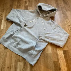 Säljer en grå hoodie från Champion i storlek L. Den är i bra skick och har en klassisk design med känguruficka och justerbar huva. Oversized passform. Champion-loggan är broderad på bröstet. Superbekväm och stilren! 🩶