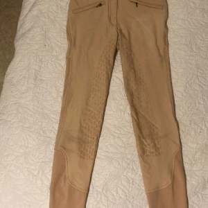 Beige ridbyxor från JH COLLECTION  - Säljer ett par snygga beige helskodda ridbyxor i stl 34. Inte mkt använda men har fått visst färgskav av sadeln (se bilder)