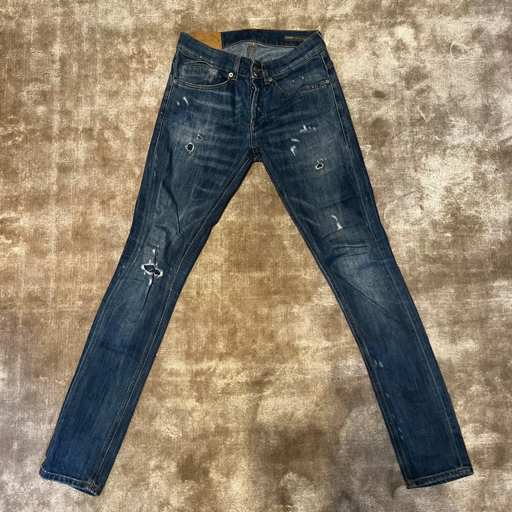 Säljer ett par snygga blå jeans från George i bra skick. De har en cool slitningseffekt och klassisk femficksdesign. Perfekta för en avslappnad stil och passar till det mesta. Midjan är midwaist och passformen är slim. Perfekta för både vardag och fest!. Farkut & Housut.