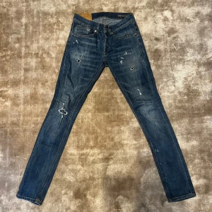 Blå jeans från DONDUP - Säljer ett par snygga blå jeans från George i bra skick. De har en cool slitningseffekt och klassisk femficksdesign. Perfekta för en avslappnad stil och passar till det mesta. Midjan är midwaist och passformen är slim. Perfekta för både vardag och fest!