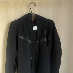 Svart Nike tech - Säljer min svarta Nike tech top från Nike store i stolen M, säljer då det ej är min stil längre. Inga skador eller annat. Toppen för 400kr och byxorna för 300 men tillsammans för 500