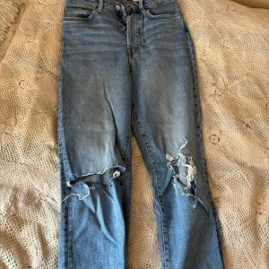 Blå mom jeans från &Denim - Säljer ett par snygga blå mom jeans från &Denim i storlek S. De är högmidjade och har en cool slitning på knäna som ger en avslappnad look. Perfekta för en casual outfit! 🦋