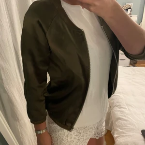 Olivgrön bomberjacka - Säljer en snygg olivgrön bomberjacka med dragkedja framtill. Jackan har spår av användning men inga hål❣️