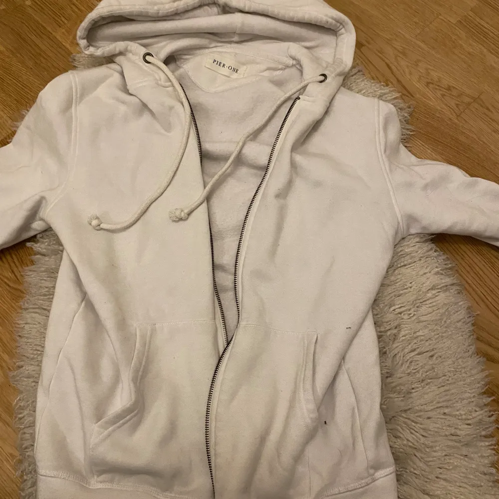 Säljer en supermjuk och bekväm vit hoodie. Den har en dragkedja framtill och en stor huva med snören. Perfekt för kyliga dagar eller mysiga hemmakvällar. Den har fickor framtill för extra komfort.. Tröjor & Koftor.