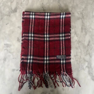 Vinröd burberry halsduk  - Skick: 8/10. Halsduken är i bra skick och har inga defekter. Mått: 147cm x 28cm 
