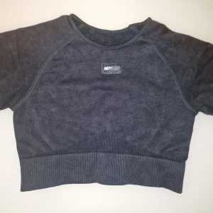 Mörkgrå croppad tröja  - Säljer en mörkgrå croped top från från Bo+Tee. Tröjan har korta ärmar och en enkel design med tight passform. Perfekt för gymmet. Garderobsrensning så kika gärna på övriga auktioner.