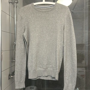 Grå tröja från Pier One - Säljer en stilren grå tröja från Pier One. Tröjan har en klassisk rund halsringning och långa ärmar. Perfekt för en avslappnad look. 