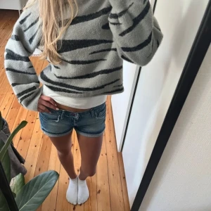 Tröja - Säljer en mysig grå tröja med svarta ränder. Tröjan har en loose passform och långa ärmar, perfekt för en avslappnad stil. Den är tillverkad i ett mjukt material som känns skönt mot huden.