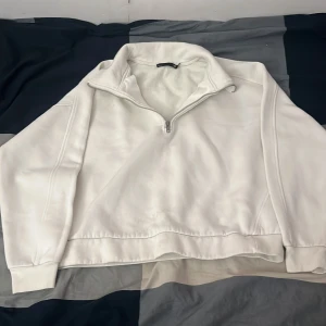 Vit fleece tröja med dragkedja - Mysig vit fleece tröja från 157 med halv dragkedja och hög krage. Perfekt för kyliga dagar med sin mjuka insida. Enkel och stilren design som passar till det mesta.