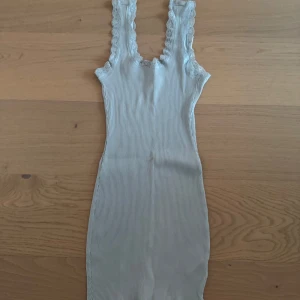 Ljusblå ribbad klänning med spetsdetaljer - Säljer en söt ljusblå ribbad klänning med spetsdetaljer vid axelbanden. Klänningen är ärmlös och har en tight passform som framhäver figuren. Perfekt för en somrig look! 💙