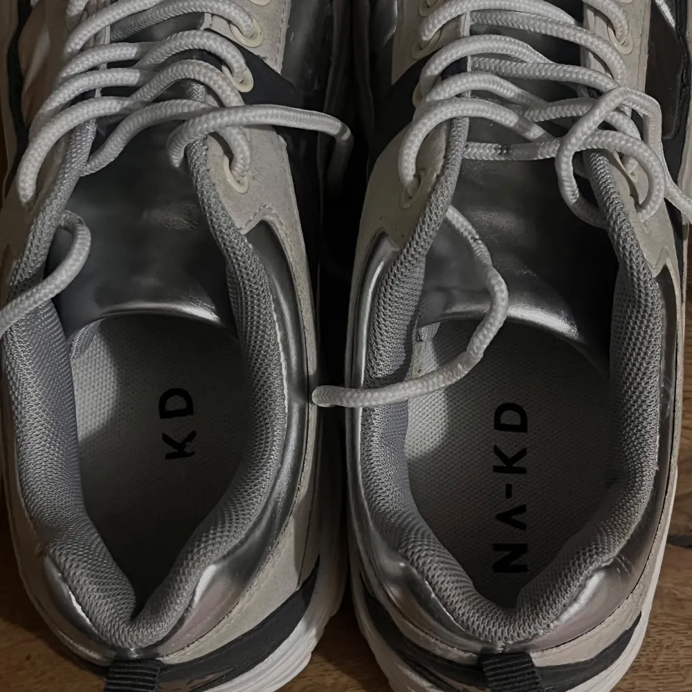 Snygga sneakers från NA-KD i en cool kombination av silver och vitt. Skorna har en chunky sula och snörning framtill. Perfekta för en trendig look.. Kengät.