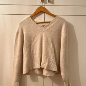 Beige stickad tröja - Mysig beige stickad tröja från Weekday i mycket bra skick. Den har en v-ringad hals och långa ärmar, perfekt för höst och vinter. Tröjan är ribbad vid ärmslut och nederkant vilket ger en snygg detalj. Superfin att matcha med jeans eller kjol! Använt då o då men i bra skick.  dzianina. biała koszula jesień