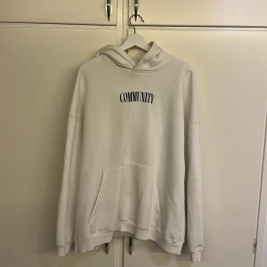 Vit Yoke’ hoodie med tryck 'Community' - Säljer en stilren vit hoodie med texten 'Community' tryckt på både fram- och baksidan. Hoodien har en klassisk design med känguruficka och en liten broderad detalj på huvan. Perfekt för en avslappnad look. Tröjan är i storlek XL (relaxed fit) och köpt för ca 1 år sedan, sparsamt använd och köpt för ca 800kr 