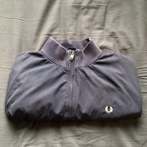 Svart windbreaker från Fred Perry - Säljer en snygg windbreaker ifrån Fred Perry. Bra skick med Inge hål eller annat slitage. Ändå defekten är att den är missfärgad vid kragen. Men det är inget som märks. Nypris ca 2500. Säljer för 250