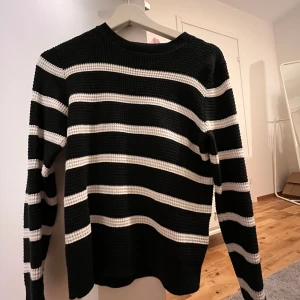 Svart och vit randig tröja - Säljer en snygg svart och vit randig tröja med långärmade ärmar. Tröjan har en klassisk design med breda ränder och är perfekt för en stilren look. Den är tillverkad i ett bekvämt material som passar bra till vardags.