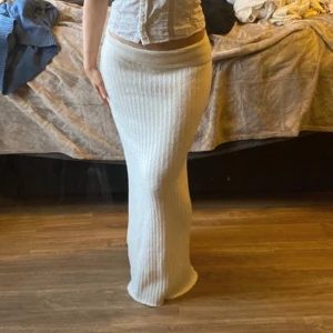 Vit ribbad långkjol - Säljer en stilren vit ribbad långkjol som är perfekt för en elegant look. Kjolen har en tight passform och är tillverkad i ett mjukt material som ger en bekväm känsla. Perfekt för att matcha med en enkel topp eller blus.