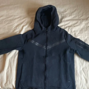 Svart hoodie från Nike - Säljer en svart hoodie från Nike med dragkedja och huva. Skicket är nästan helt nytt bara, bara använt den ett fåtal gånger. Perfekt för en casual look eller träning.