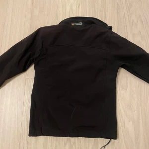 Svart jacka från Peak Performance - Snygg svart jacka från Peak Performance med dragkedja framtill och två praktiska fickor med dragkedjor. Perfekt för kyligare dagar med sin stilrena design och bekväma passform.