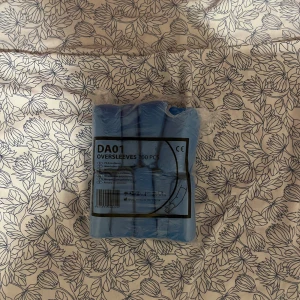 Blå engångsärmar DAO1 - Paket med 100 stycken blå engångsärmar DAO1. Perfekta för att skydda kläder vid olika aktiviteter. Tillverkade av lätt och slitstarkt material. Praktiska att använda i miljöer där hygien är viktigt.