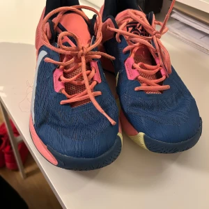 Giannis Immortality basketskor - Snygga Nike sneakers i en fräsch kombination av blått och rosa med vita detaljer. Skorna har en sportig design med snörning och en bekväm sula. Perfekta för en aktiv livsstil.