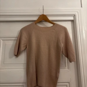 Beige kashmirtröja från H&M - Säljer en mjuk och stilren beige kashmirtröja från H&M. Tröjan har en ribbad design och trekvartsärmar, perfekt för en elegant och bekväm look. Passar utmärkt till både vardag och mer uppklädda tillfällen.