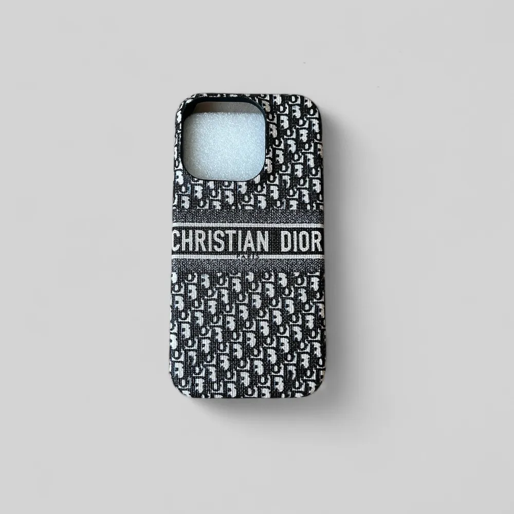 Snyggt mobilskal från Christian Dior med ett klassiskt mönster i svart och vitt. Skalet har en stilren design med märkets logotyp tydligt synlig. Perfekt för att ge din telefon en lyxig touch. . Asusteet.