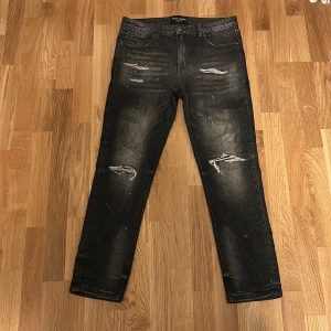 Svarta jeans från Supply & Demand - Snygga svarta jeans med slitna detaljer från Supply & Demand. De har en dragkedja och knapp framtill samt klassisk femficksdesign. Perfekta för en avslappnad stil med en edgy touch.