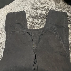 Svarta byxor från Epperson of Sweden - Snygga svarta byxor från Epperson of Sweden i bomull. De har en klassisk design med bälteshällor och knäppning fram. Perfekta för en stilren look.