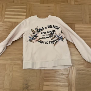 Ljusrosa  tröja från Zadig & Voltaire - Säljer en ljusrosa tröja från Zadig & Voltaire med tryck och blommönster framtill. Tröjan har långa ärmar och en avslappnad passform. Perfekt för en stilren och bekväm look.