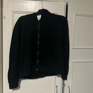 Svart tröja  - Säljer en stilren svart tröja med dragkedja framtill. Tröjan har långa ärmar och en klassisk design som passar perfekt för en cool och avslappnad look.