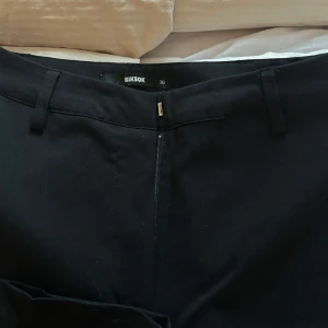 Svarta kostymbyxor från Bik Bok - Svarta raka högmidjade kostymbyxor från BikBok i strl 36. Använda 1 gång tills jag insåg att jag köpt fel modell och nu bara ligger i garderoben. Nypris på dessa 499kr! 