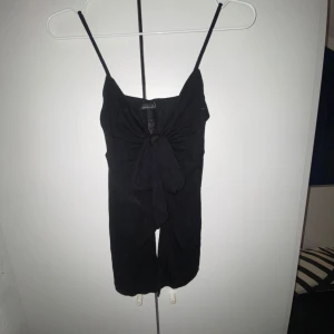 Svart axelbandslös topp från Gina Tricot - Snygg svart axelbandslös topp från Gina Tricot med knytning framtill. Perfekt för en het sommardag om du vill matcha vädret🙃🔥🧑🏽‍🚒.  Tillverkad i ett mjukt material som ger en bekväm och snygg passform.⌛️⌛️