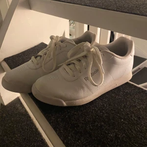 Vita sneakers från Reebok - Säljer ett par klassiska vita sneakers från Reebok. Skorna har snörning och en stilren design med Reebok-loggan på sidan och hälen. Perfekta för en avslappnad stil. Använda några gånger men bra skick.